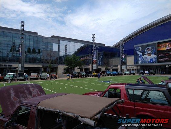 1996 Ford Bronco and other vehicles parked on a football field in front of a stadium