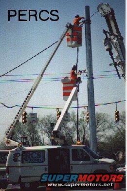 White utility van with PERCS logo parked below bucket trucks working on power lines