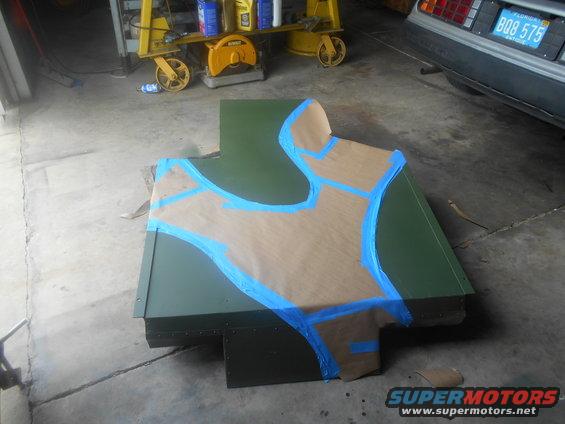 Green metal part with masking tape pattern on a concrete floor