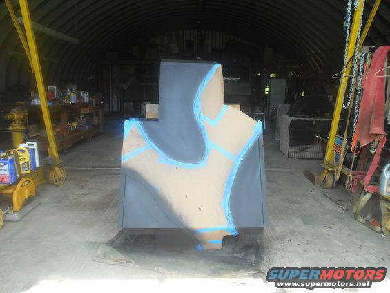 Unfinished object with blue tape and gray paint in a garage