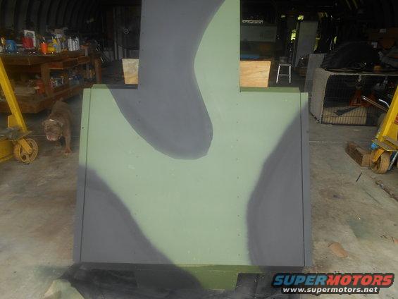 Camouflaged panel in a garage with a dog and tools