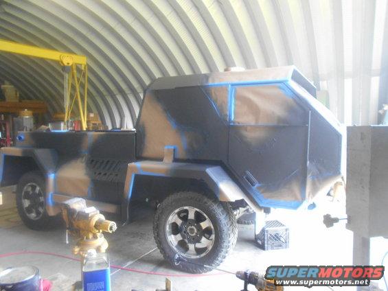 Armored vehicle with camouflage paint scheme being worked on inside a building