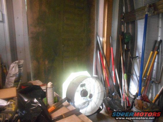 Interior of a storage shed with tools, a fan, and a bag of something