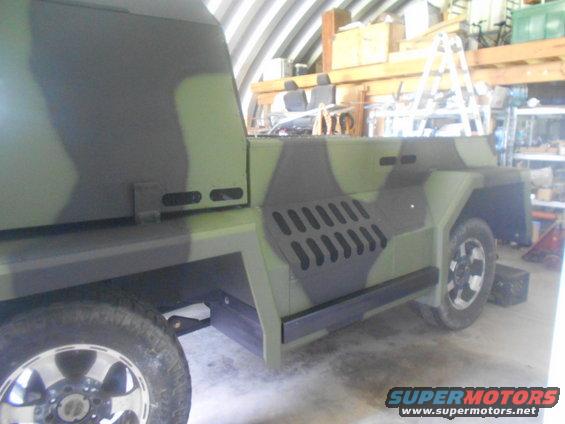Custom camouflage vehicle in a garage, side view. Looks like a modified truck or SUV