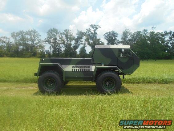 Camouflaged truck with large tires parked in a grassy field