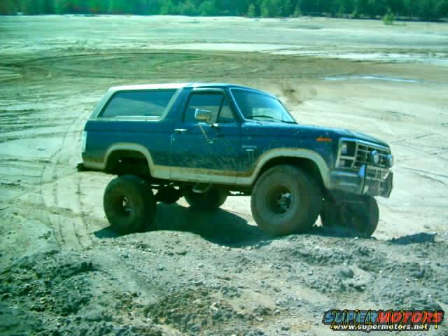 Blue lifted Ford Bronco on dirt terrain