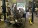 1979 Jeep CJ5 - Mechanics work on the engine of a 1979 Jeep CJ5 chassis in a garage, with a Texas license plate visible.