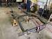 1979 Jeep CJ5 - A vehicle frame is supported by jack stands in a garage setting.