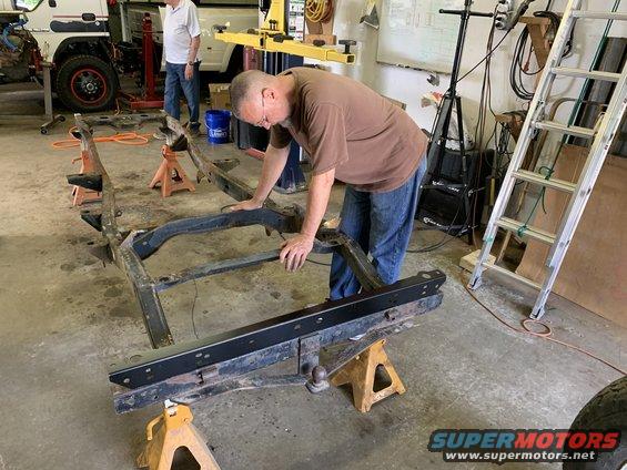 man working on vehicle frame on jack stands in garage