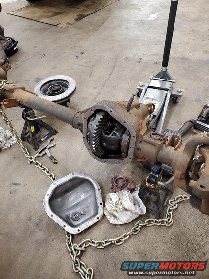 Ford Dana 50 front axle with differential cover removed, sitting on jack stands with a jack behind it