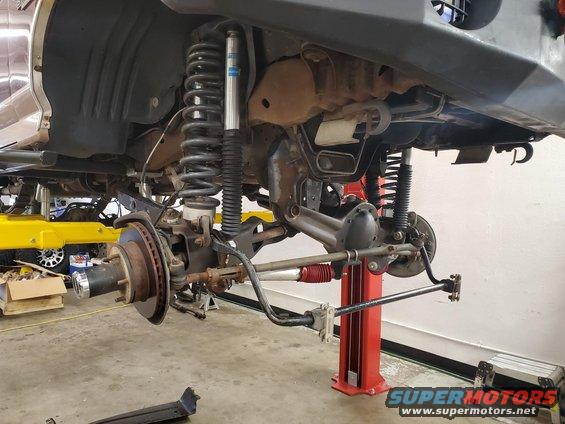 Front suspension and axle assembly on a lift, showing Bilstein shocks and heavy-duty components