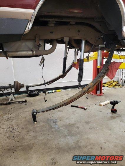 vehicle's rear suspension disassembled with leaf springs and shocks removed, on a lift