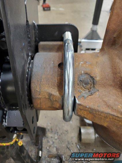 close-up of rusty metal part with a silver loop attached, likely part of a vehicle's suspension or frame