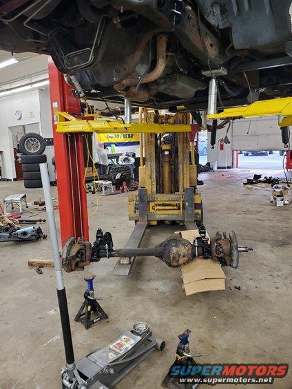 Front axle assembly on jack stands with a forklift in background