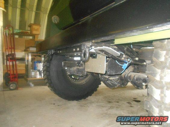 Rear axle and tire of a large vehicle, showing suspension components and a tow hitch receiver