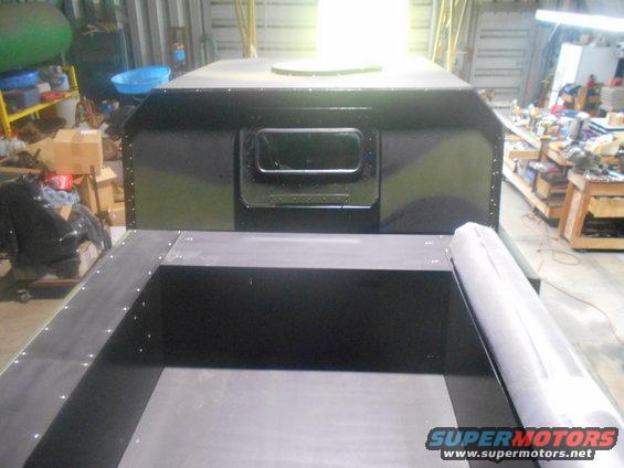 Interior of a workshop showing a custom-built truck bed with black metal framing and a central black box