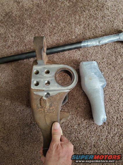 Rusty steering knuckle with metal plate and tie rod on carpet