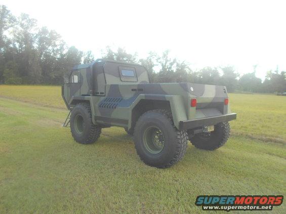 Camouflaged military truck with large tires parked on a grassy field