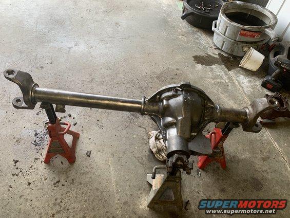 Rear axle assembly on jack stands, with oil drain pans and tools in background
