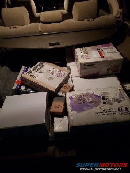 Vehicle cargo area interior with boxes of parts, including one labeled 'PERFORMANCE TRAIN'