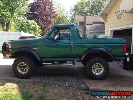 Green 1996 Ford Bronco with lifted suspension and large off-road tires parked on a driveway