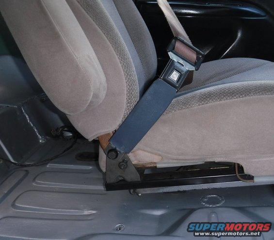One of the F-series bench seat belts ended up working well, with a trimmed sleeve, along with the Windstar's seat back bolt.  You can see a forward facing triangular indentation in the fabric.  There was a bracket there that I don't recall the purpose of (probably held a trim piece on that I long ago removed), so I used its hole for a temporary pivot stop to keep the seat belt from clanging against the floor and being difficult to retrieve.