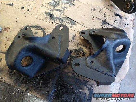 Two black painted metal suspension brackets on a work surface