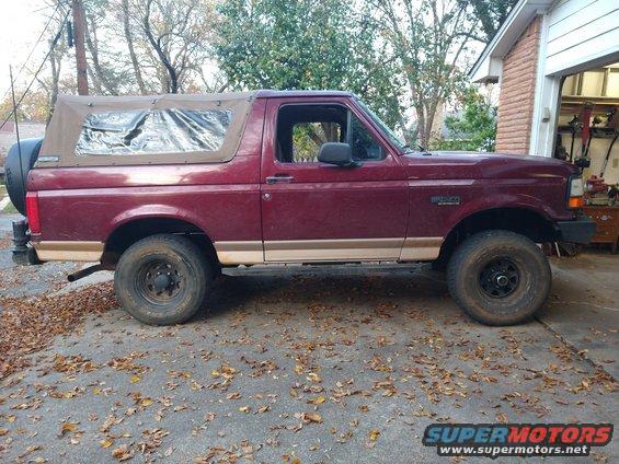 Maroon 1996 Ford Bronco side view with tan soft top