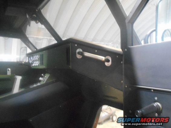 Interior view of a dark-colored vehicle with a grab handle and dashboard details