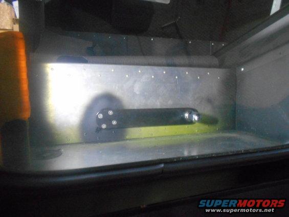 Interior view of a vehicle's cargo area with a metal panel and a black rod attached