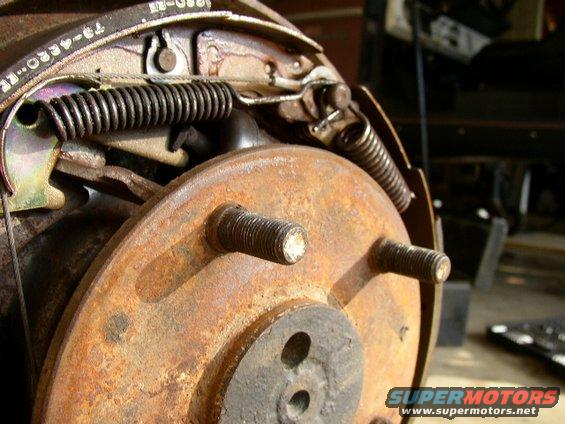 Close-up of a rusty brake drum with shoes and springs visible. Part number 79-4330-ER is visible on the brake shoe