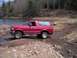 1994 Ford Bronco - A red Ford Bronco navigates a rocky stream bed in a wooded area.