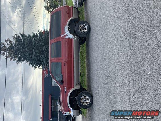Red and tan Ford Excursion parked on asphalt, side view. "EXCURSION" badge visible