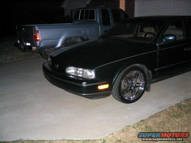 Dark sedan with chrome wheels parked next to a blue pickup truck