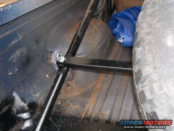Spare tire and blue tarp in cargo area of vehicle, with metal bracing