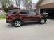 2016 Ford Explorer - Side view of a red 2016 Ford Explorer parked outside a brick house with a garage.
