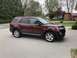 2016 Ford Explorer - A brown 2016 Ford Explorer is parked on a concrete driveway in front of a residential house.