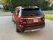 2016 Ford Explorer - 2016 Ford Explorer XLT in red, seen from the rear on a paved surface with trees in the background.
