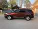 2016 Ford Explorer - A red 2016 Ford Explorer is parked in front of a house on a sunny day.