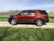 2016 Ford Explorer - This 2016 Ford Explorer is seen from the side, parked on a gravel road with a grassy field and trees behind it.