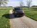 2016 Ford Explorer - 2016 Ford Explorer on a gravel driveway with green fields and trees in the background.