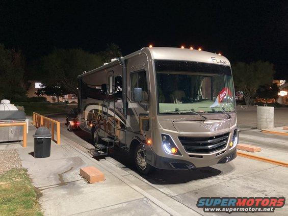 Motorhome parked at night, showing front and side. Has a FLAR badge on top
