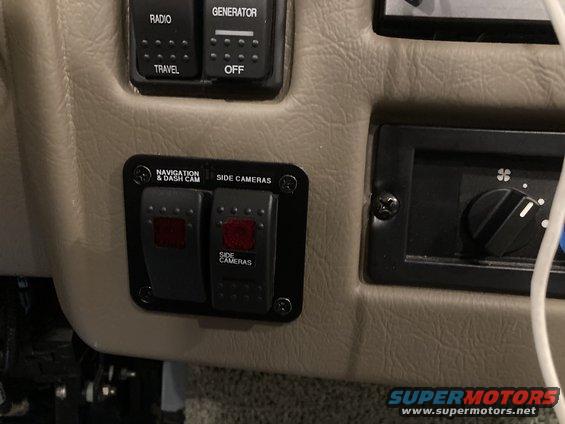 Control panel with buttons for radio, generator, navigation, and side cameras. Also has a climate control knob