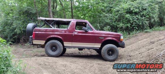 Maroon 1996 Ford Bronco with tan trim and soft top on an off-road trail