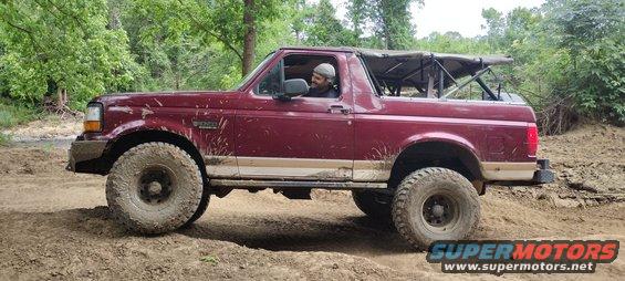 Red 1996 Ford Bronco side view, off-road tires, soft top
