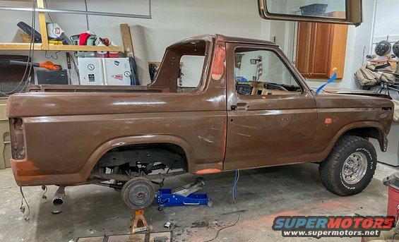 Brown 1984 Ford Bronco on jack stands in a garage, undergoing restoration