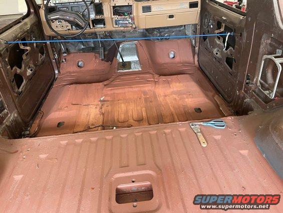 Brown interior of a disassembled 1980s SUV with red primer on the floor and door panels removed