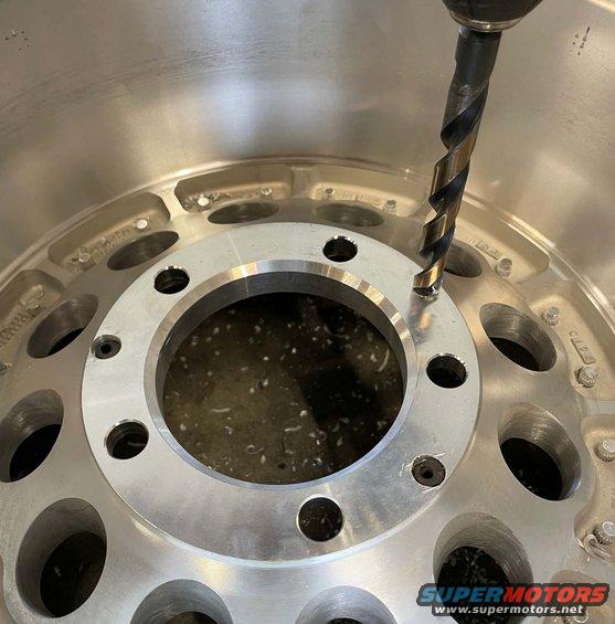 Drilling a hole in a silver alloy wheel with a drill bit