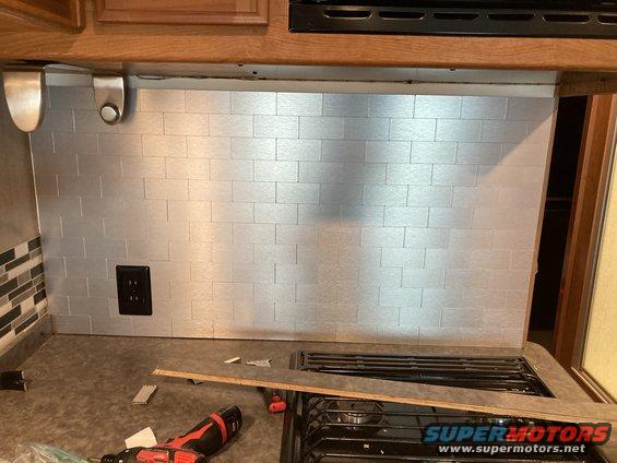 Silver subway tile backsplash above stovetop with power outlet