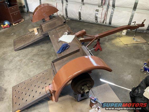 Trailer frame with fenders and wheel assembly, undergoing painting